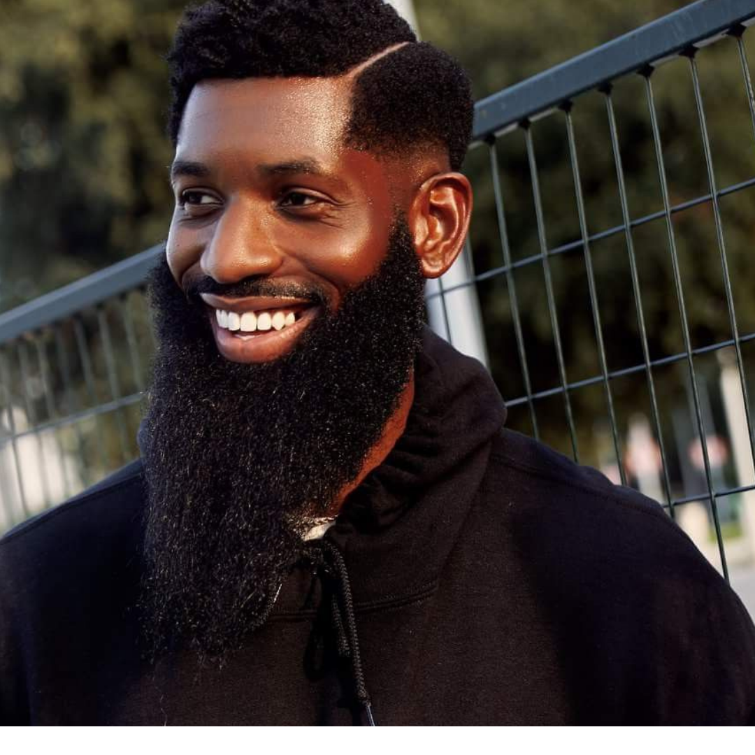 Black man smiling showing his teeth with a full lengthy beard